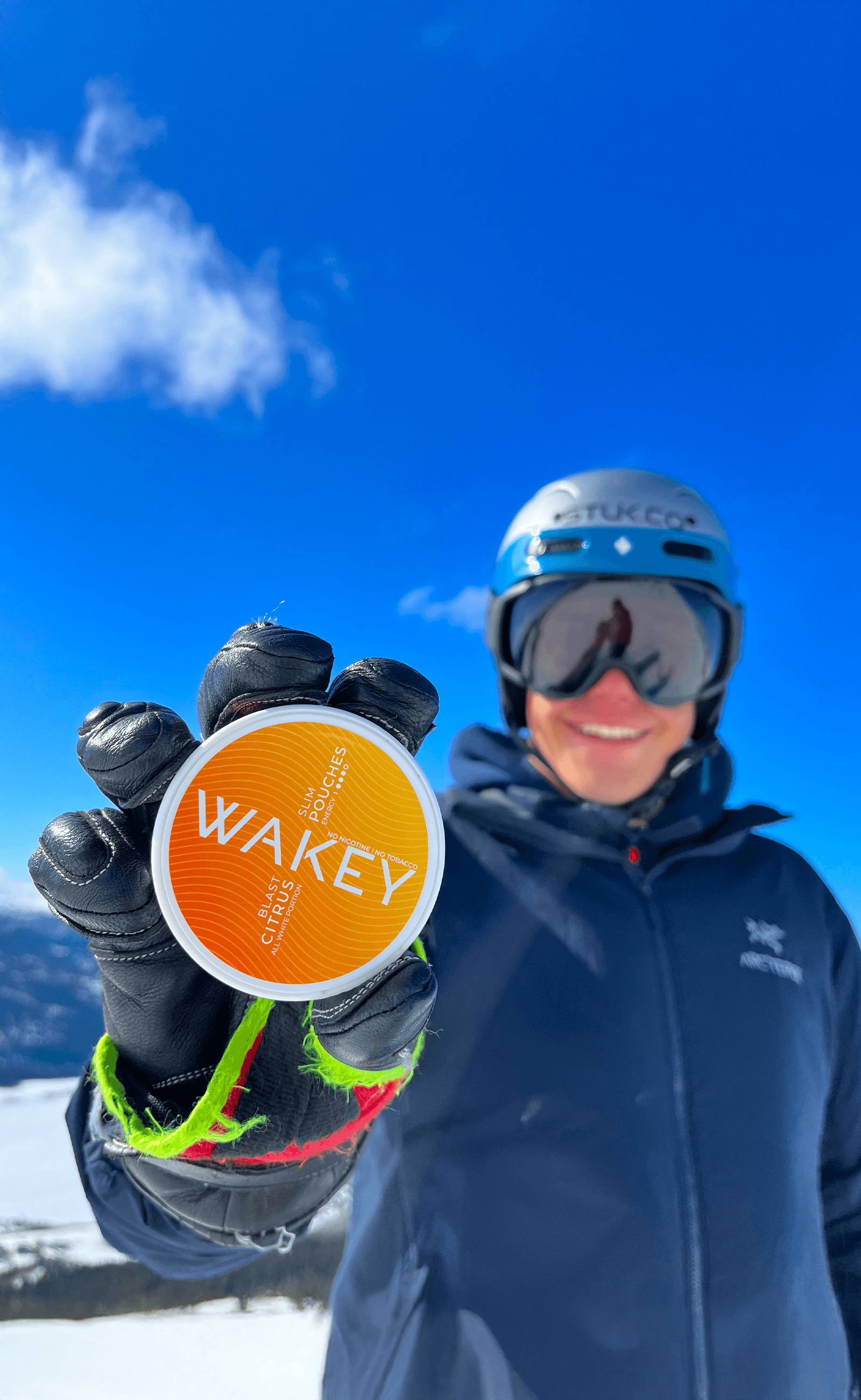 Skier holding a Wakey Citrus Blast tin on a mountain