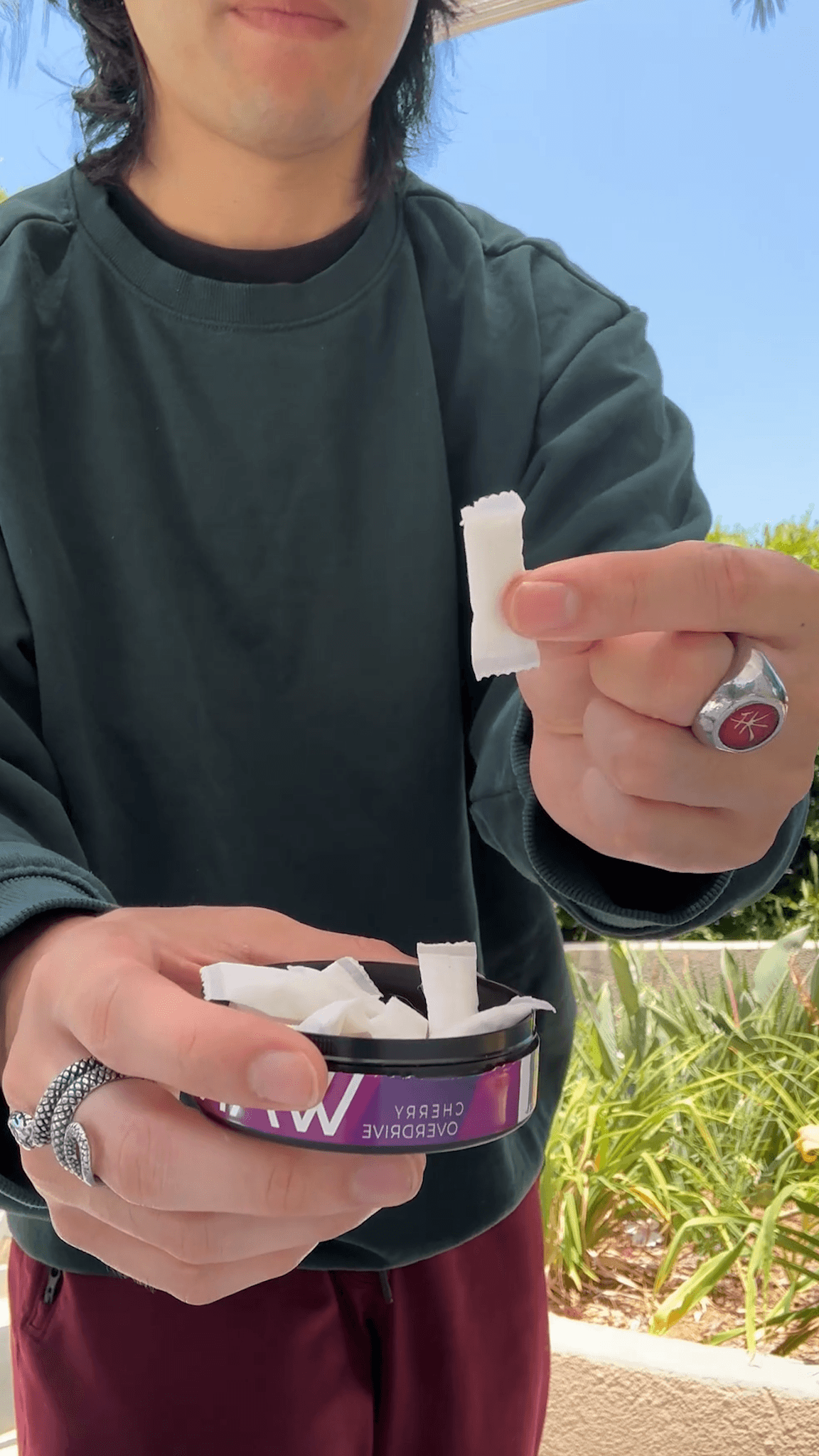Person holding a Wakey pouch and an open Cherry Overdrive tin outdoors